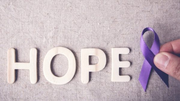 Four wooden letters spelling "HOPE" with a purple ribbon to the right-hand side representing fibromyalgia awareness.