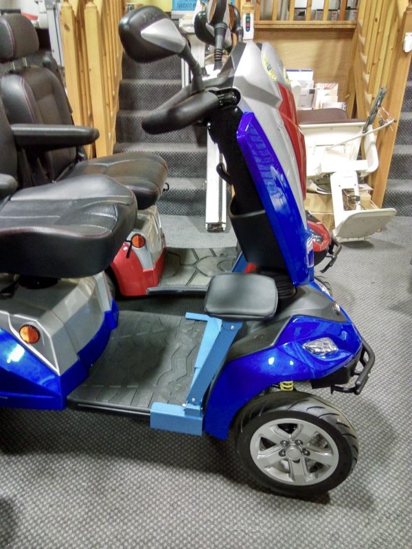 A metallic blue four wheeled mobility scooter with two light blue Comfyrider leg rests. 
