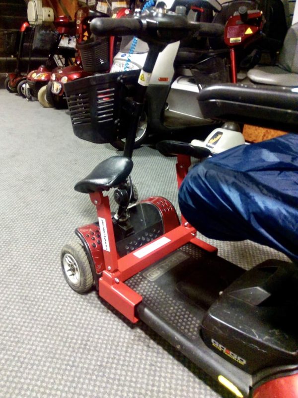 A matt red four-wheeled mobility scooter with two matching Comfyrider leg rests. 