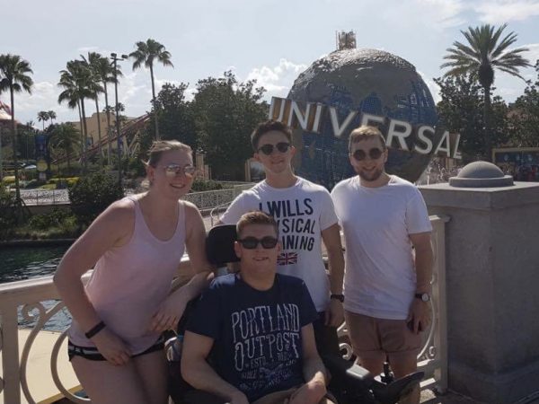 A group photo of four people, including Daniel. They are outdoors, smiling at the camera, and there are palm trees and the Universal logo behind them.