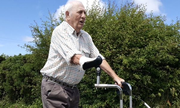 A walking aid with a custom raised handlebar on one side that is shaped to fit and support the gentleman’s amputated arm.